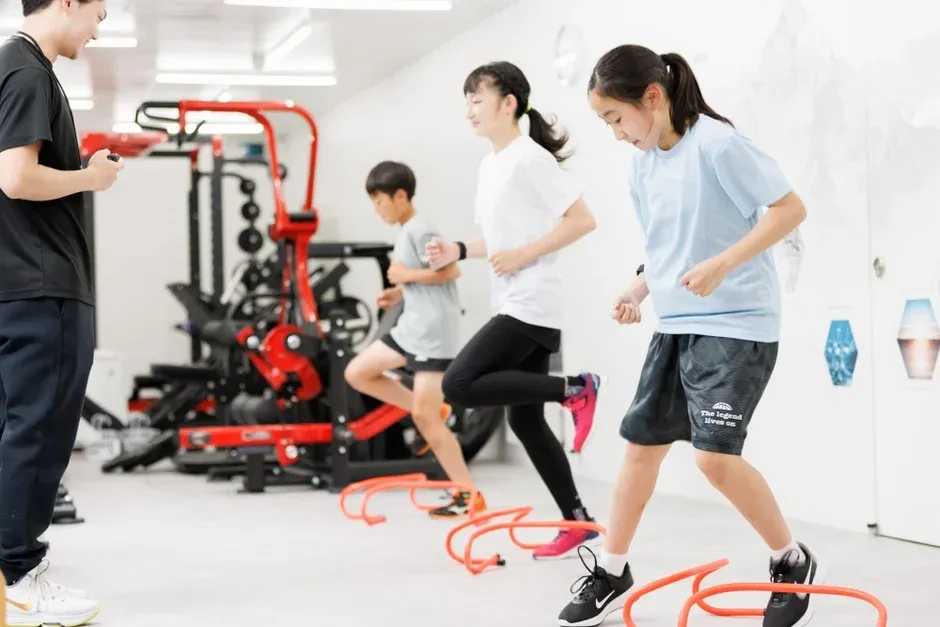 室内でトレーナーが子供たちにアジリティートレーニングを指導している様子