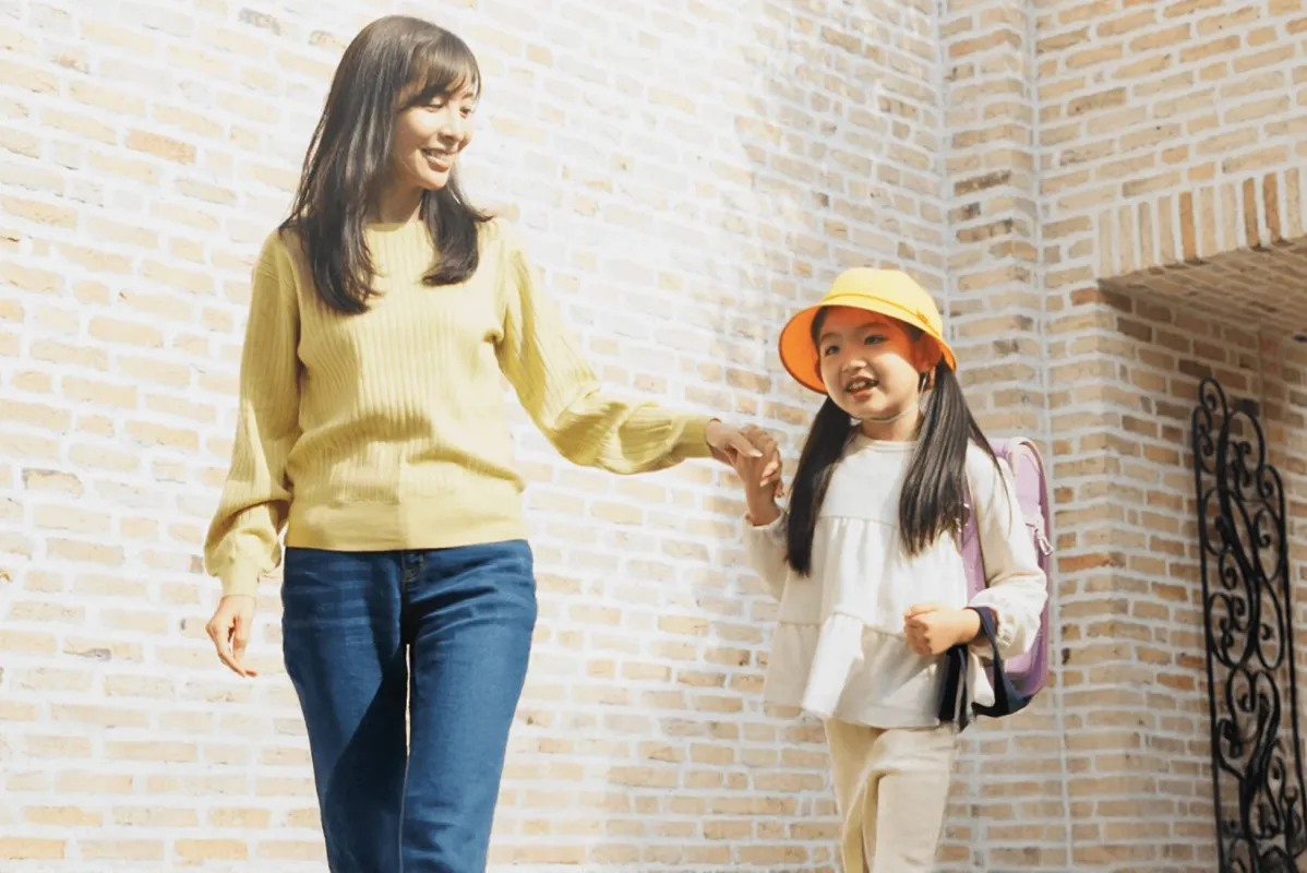 笑顔の母娘が手をつないで歩いている