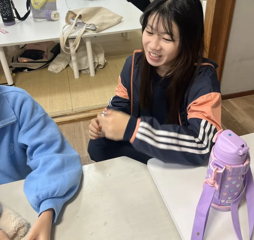 室内で笑顔の若い女性がテーブルに座り、楽しそうに話している様子