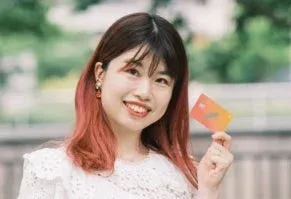 笑顔の若い女性が屋外でカラフルなカードを手にしています。