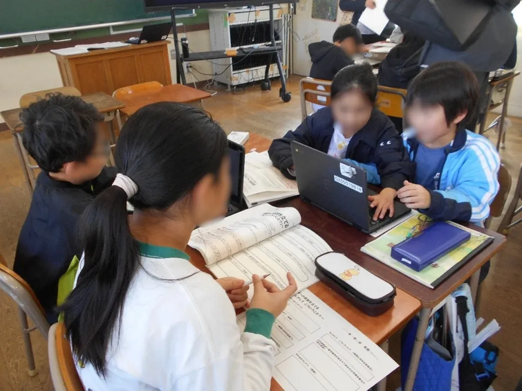 小学校の教室で、児童がノートパソコンやワークシートで学習。ICT教育