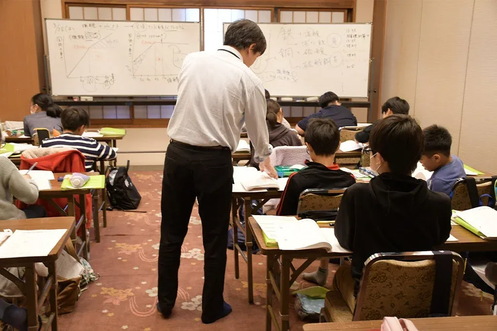 教室内でホワイトボードを使って授業を行う教師と生徒たち