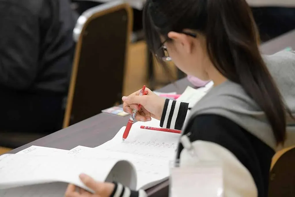 眼鏡をかけた学生がノートに書き込んでいる様子