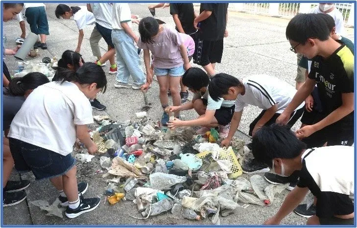 屋外でゴミ拾い活動をする子供たちの様子