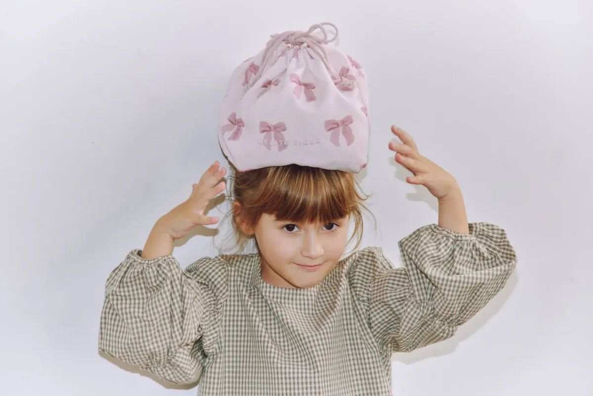 リボン柄の巾着袋を頭に乗せる女の子