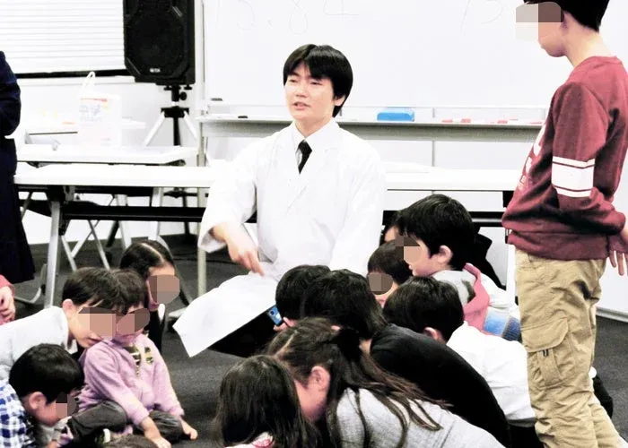 科学教室で先生の話を聞く子供たち