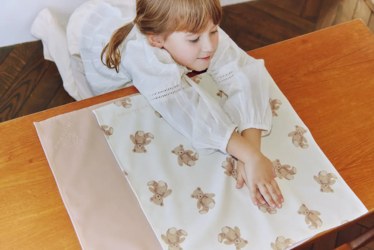 クマ柄のランチョンマットを見る女の子