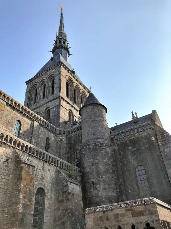 青空を背景にそびえ立つ、石造りの壮大な修道院の尖塔と建物の側面を捉えた写真です。