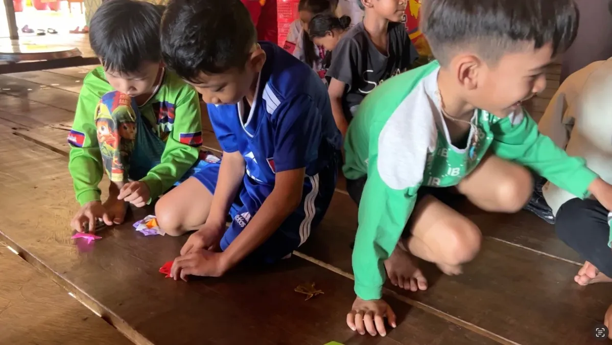 木の床にしゃがんで小さなカラフルな物体で遊ぶ子供たちの様子