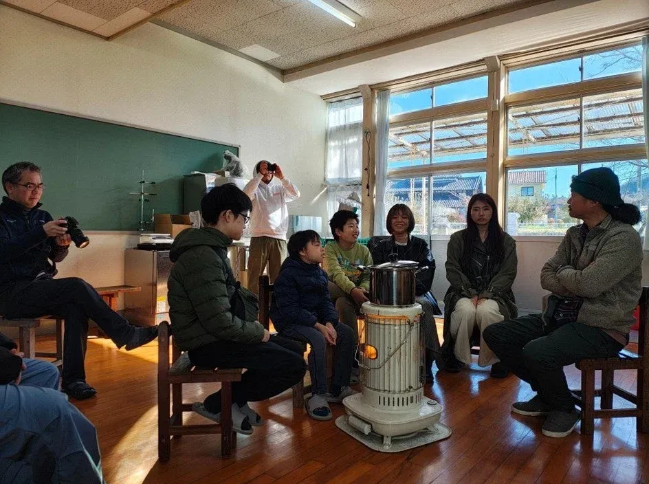 石油ストーブを囲んで交流する大人と子供たち