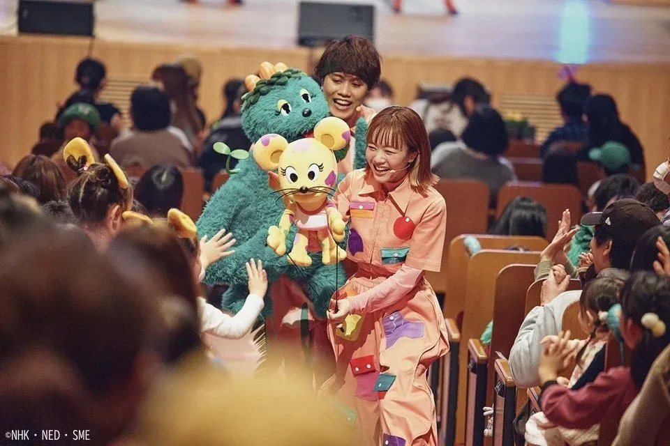 舞台上で着ぐるみとパペットを交え、パフォーマーが観客と楽しげに交流しているショーの一場面