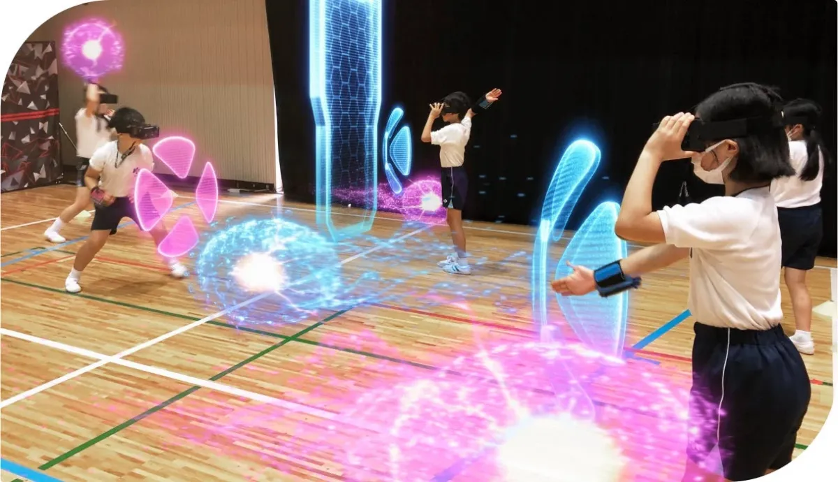 体育館で数人の子供たちがVR/ARヘッドセットと腕のデバイスを装着し、仮想のデジタルオブジェクトとインタラクションしている様子。未来的な教育やゲーム体験をしているようです。