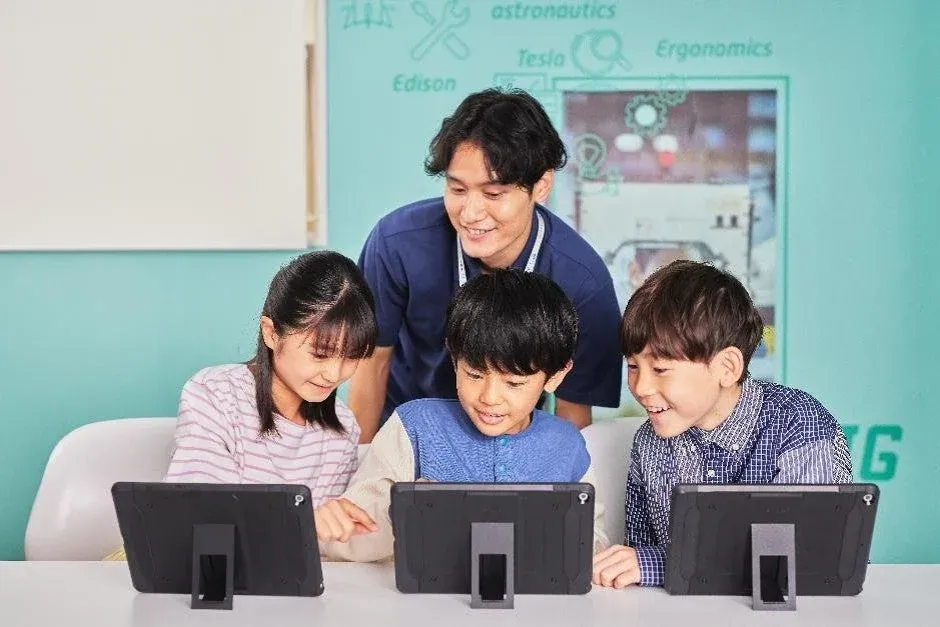 先生とタブレットで学習する子どもたち