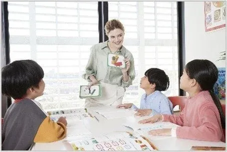 女性の先生が3人の子供たちにフラッシュカードを使って教えている学習風景