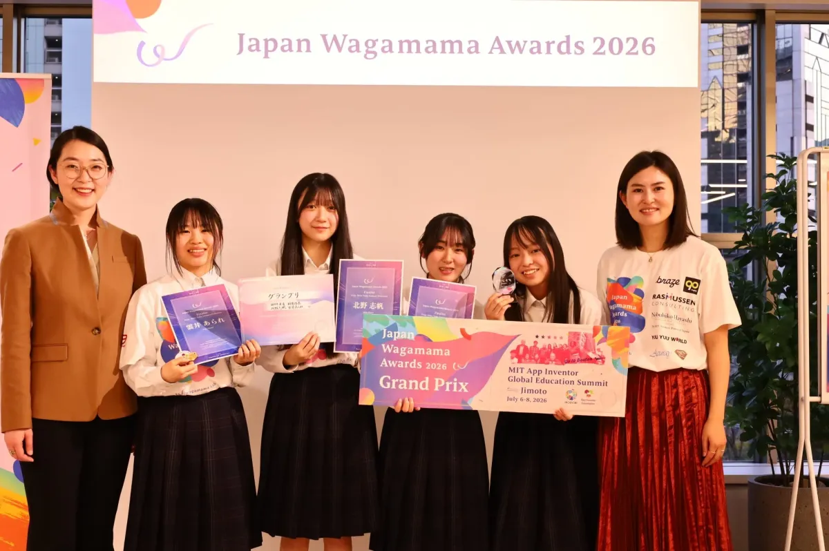 Japan Wagamama Awards 2026の授賞式で、女子学生たちがグランプリやファイナリストの表彰状、トロフィーを手に笑顔で記念撮影をしています